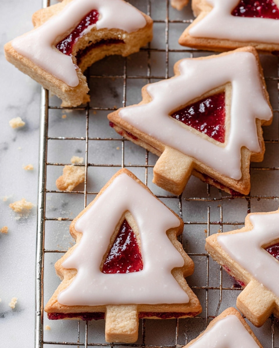 The image shows several tree-shaped sandwich cookies with three layers: a bottom cookie layer in light golden brown, a middle bright red jam layer visible through a small diamond-shaped cutout, and a top cookie layer covered with smooth, glossy white icing. The cookies are placed on a silver wire cooling rack set on a white marbled surface. Crumbs are scattered around, and one cookie at the top left has a bite taken out, showing the soft texture inside. Photo taken with an iphone --ar 4:5 --v 7