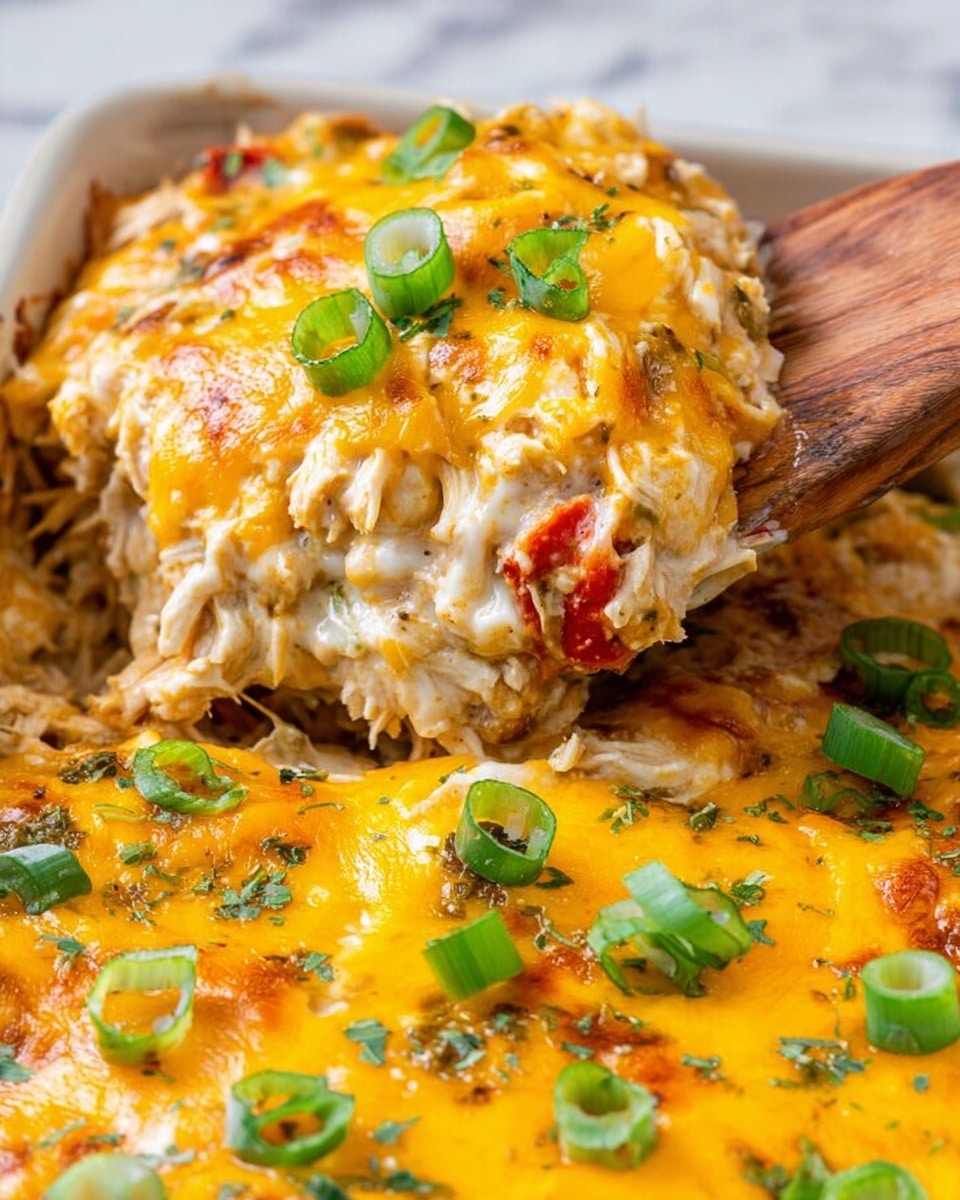 The image shows a close-up of a cheesy baked dish being scooped with a wooden spatula, with a woman's hand holding the spatula. The dish has two main layers: the bottom layer is creamy with melted white cheese mixed with shredded chicken and bits of red tomato. The top layer is golden-yellow melted cheddar cheese, generously covering the dish. Slices of bright green scallions are scattered on top, along with small sprinkles of chopped fresh green herbs. The dish sits on a white marbled surface. Photo taken with an iphone --ar 4:5 --v 7