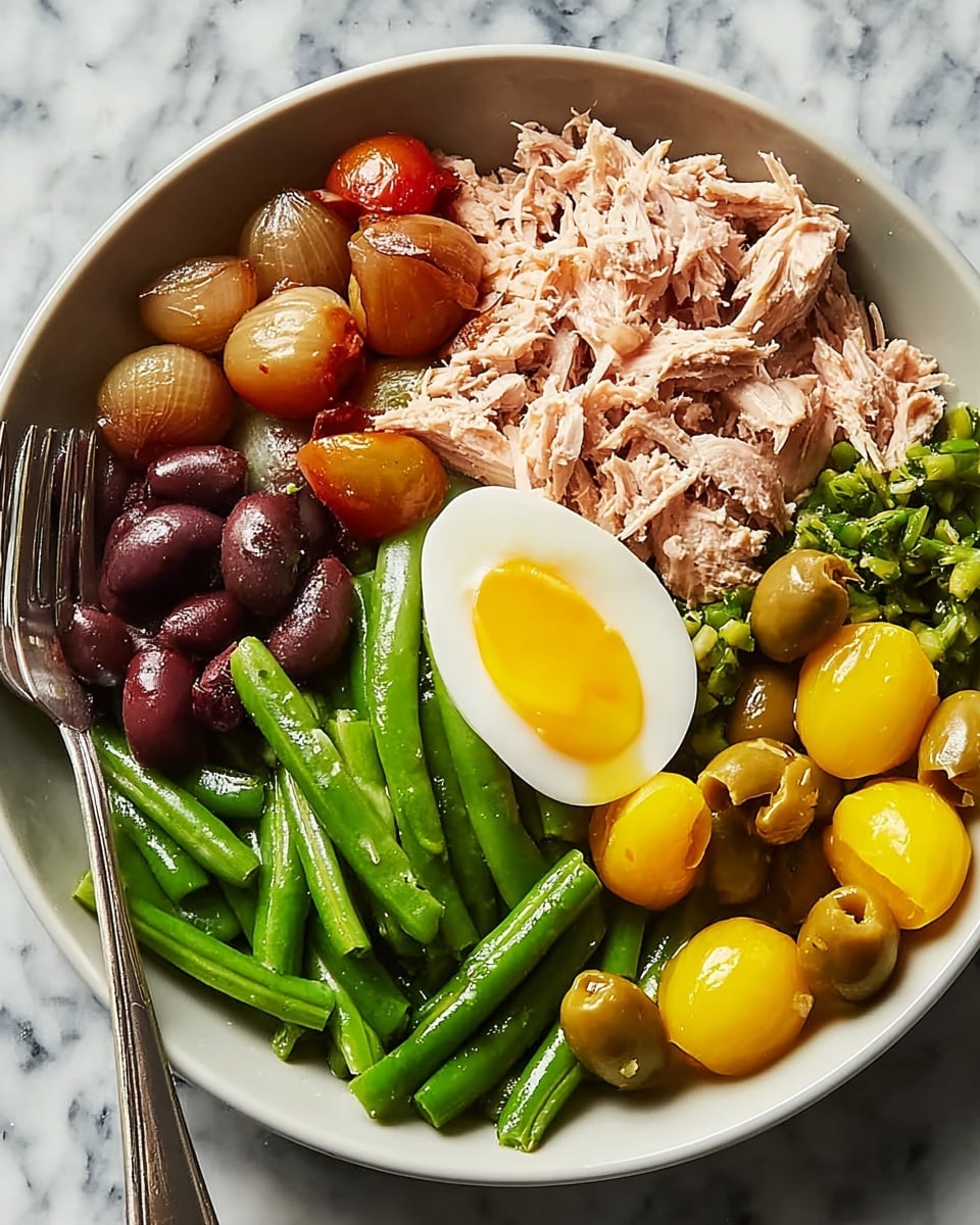 A bowl filled with different foods arranged in separate sections: at the top left, small roasted onions with a light brown, slightly charred skin; below them, light pinkish pieces of shredded tuna mixed with dark brown olives. To the right, a layer of bright green beans with bits of minced garlic on top, and next to them on the bottom right, shiny yellow cherry tomatoes along with bright green olives. At the center, half a soft-boiled egg showing a glossy yellow yolk and a white outer part. The bowl is white on a white marbled surface with a silver fork resting on the edge. photo taken with an iphone --ar 4:5 --v 7