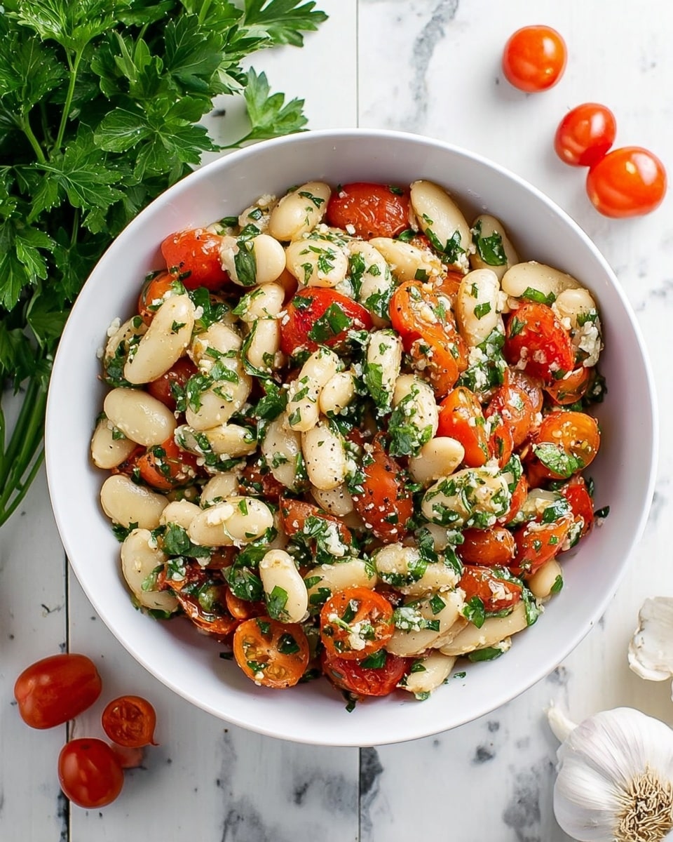 A white bowl filled with a colorful salad sits on a white marbled surface. The salad has three main layers visible: large white butter beans with a smooth texture, halved bright red cherry tomatoes, and finely chopped fresh green herbs that are scattered evenly throughout. Small bits of white garlic or cheese are mixed in, adding texture contrast. The salad looks fresh and lightly seasoned with visible pepper. Around the bowl, a bunch of fresh green parsley, whole garlic bulbs, and whole cherry tomatoes are placed casually. The photo taken with an iphone --ar 4:5 --v 7